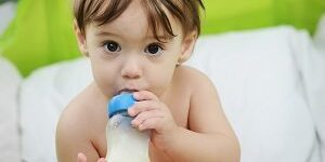 Beautiful little baby with a milk bottle in bed baby bottle, tooth decay
