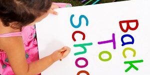 Girl Writing Back To School As Symbol For Education back to school, girl in grass, sign