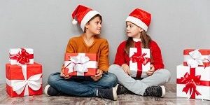 Two cute children in santa claus hats holding gift boxes Protect child's teeth during holidays
