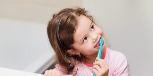 Little girl in pink pyjamas in bathroom brushing teeth oral hygiene