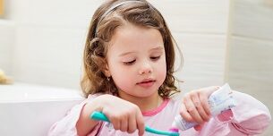 Little girl in bathroom putting a toothpaste on toothbrush toothpaste, san diego kid's dentist, kid's dentist near me, children's dentist san diego, abc children's dentistry,