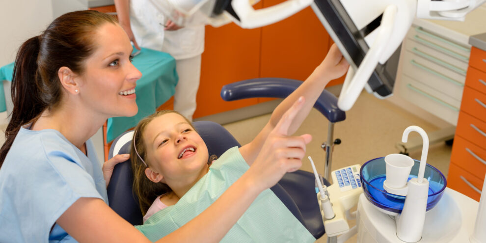 Dentist showing child dental procedure on monitor