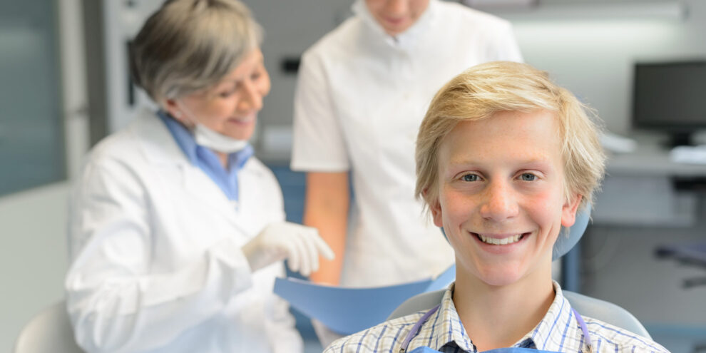 Teenage patient, dentist woman with dental assistant